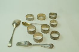 A collection of eight silver and silver coloured napkin rings; a silver serving spoon;