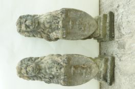 A pair of reconstituted stone figures of heraldic dogs, each holding a shield,