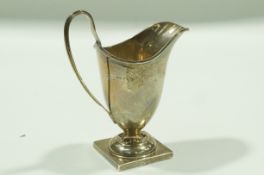 A silver cream jug, Chester 1937, of helmet shape in the Georgian style, to a square foot,