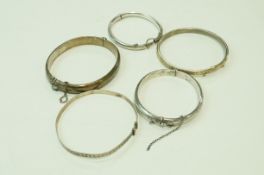 A silver hinged bangle; another similar bangle; another smaller example; a baby bangle;
