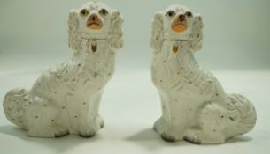 A pair of Staffordshire pottery figures of spaniels, decorated in gilt and enamels,
