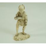 A late 19th century Japanese carved ivory figure, holding a parcel on a mound base, 10.