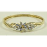 A tanzanite and diamond hinged bangle, stamped '9K',