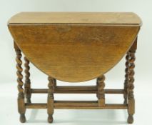 An oval oak drop leaf table with barley twist legs, 73cm high, 90cm wide,