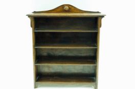 An oak standing bookcase, the raised arched back with an applied roundel,