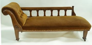 An Edwardian chaise longue, with oak frame, flared legs and casters,