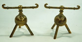 A pair of brass fire dogs, after a Christopher Dresser design, on three splayed legs,
