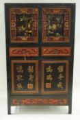 A Chinese carved and lacquered standing cupboard with 2 doors above 2 drawers above 2 further