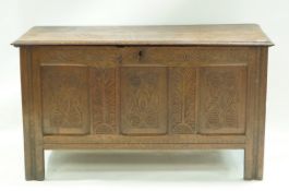 An oak coffer with carved triple panelled front and two wrought iron ring handles, 64cm high,