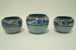 A set of chameleon jardinieres each decorated with an Art Nouveau band of flowers on a mottled blue