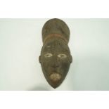 A carved Igbo face mask, painted black, with red and white highlights,