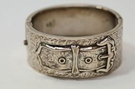 A silver hinged bangle, Birmingham 1936, in the Victorian style of a buckle to an engraved ground,