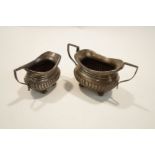 A silver sugar bowl and cream jug, Birmingham 1902, of rounded rectangular gadrooned form,
