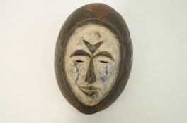 A carved Igbo face mask, with white painted face,