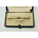 A 9 carat gold ruby and diamond three stone bar brooch, 5.6 cm long, 1.