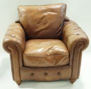A leather armchair with button arms, loose cushion to the back and another to the seat,