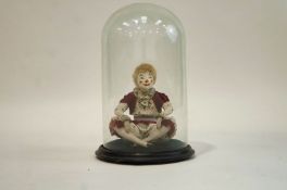 A Victorian glass dome on ebonised stand enclosing a figure of a clown. 41cm high x 27cm diameter.