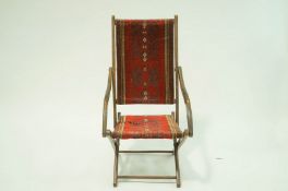 A 19th Century mahogany folding armchair with Turkey carpet back and seat