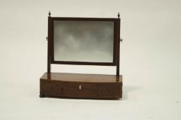 A Victorian swing mirror on a bow front base, with three drawers on bun feet,