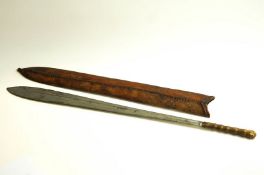A tribal short sword/machete in leather scabbard and ridged handle, 63.