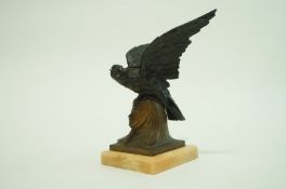 A spelter watch stand in the form of an eagle with snake in his beak perched on an Egyptian bust on