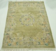 A Chinese silk rug, with central medallion of flowers on a pale green field.