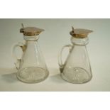 A matched pair of silver mounted glass whisky noggins, one Birmingham 1909, the other marks worn,