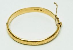 A 9ct gold hinged bangle, Birmingham 1965, of hollow D section and fully engraved, 0.9 cm wide, 6.