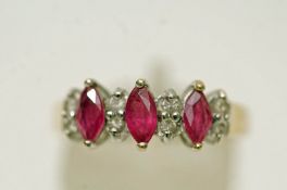 A three stone ruby 9 carat gold ring, the marquise cuts with pairs of small brilliant cuts between,