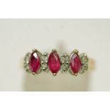 A three stone ruby 9 carat gold ring, the marquise cuts with pairs of small brilliant cuts between,