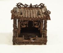 A Chinese wooden 'Spirit house', well carved with dragons and birds of paradise, with a tiled roof.