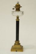 A Victorian brass column oil lamp with a clear glass reservoir, with applied retailers label, W.
