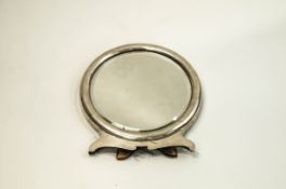 A silver mounted round dressing table mirror with a shaped base and an easel back,
