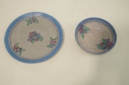 A Crown Ducal bowl and charger, each decorated with flowers on a blue ground.