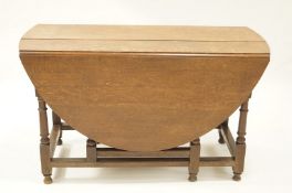 An oak drop leaf table with turned legs linked by rectangular stretchers, 75cm high x 128.