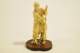 An early 20th Century ivory figure, in the form of a duck hunter, mounted on a wooden base, 11.