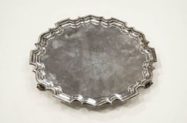 A silver salver with a Chippendale border on three leaf-scroll feet,