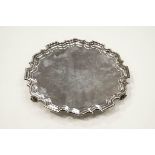 A silver salver with a Chippendale border on three leaf-scroll feet,