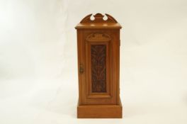 A stripped walnut Victorian bedside cabinet with carved door