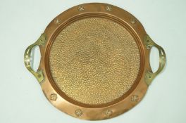 A copper Arts and Crafts round twin handled tray,with hammered finish to the centre,