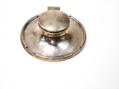 A silver capstan shaped inkwell, with a crenellated border and a ceramic liner,