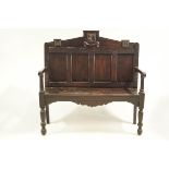 An 18th century and later oak hall bench, the panelled back with cresting rail,