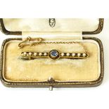 A sapphire and seed pearl brooch, the round cut stone flanked either side by a row of split pearls,