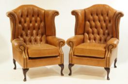 A pair of 20th Century tan leather button back armchairs, each with cabriole legs.