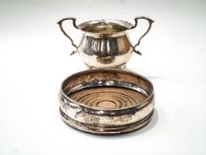 A silver round sugar bowl with a shaped border, two double - scroll handles and four pad feet,