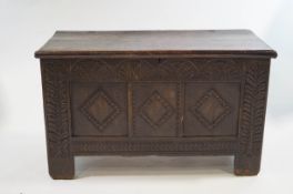 An 18th Century oak coffer on a tinted, carved in relief to the front and side panels,