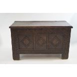 An 18th Century oak coffer on a tinted, carved in relief to the front and side panels,