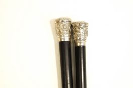 A pair of ebonised walking canes, with Indian white metal mounts,