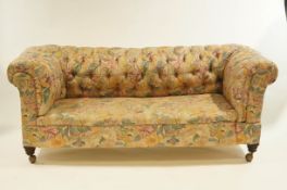An early 20th Century drop end Chesterfield sofa on mahogany legs and metal castors,