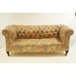 An early 20th Century drop end Chesterfield sofa on mahogany legs and metal castors,